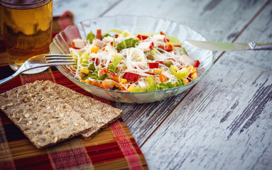salad of Chinese rice glass noodles with vegetables and crab sticks,  glass of apple juice served on table. photo toned with vignette