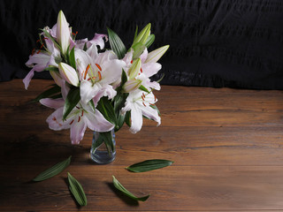 Still life with pink lilies on a wooden surface.