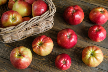 basket with red ripe apples on a brown wooden table