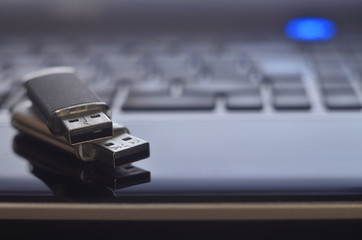 USB flash cards lying on black laptop case in front of his keyboard. Virtual memory storage with...