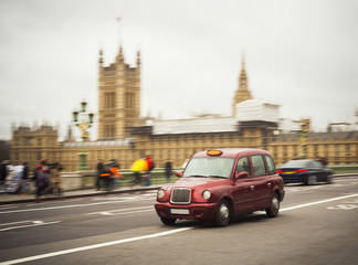 red taxi cab driving in central London city, United Kingdom