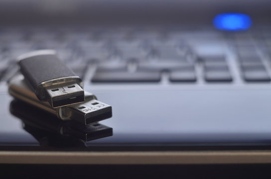 USB flash cards lying on black laptop case in front of his keyboard. Virtual memory storage with USB output
