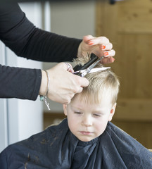 Obraz na płótnie Canvas Male child at the barber shop to cut the hair. cute young boy getting a haircut.