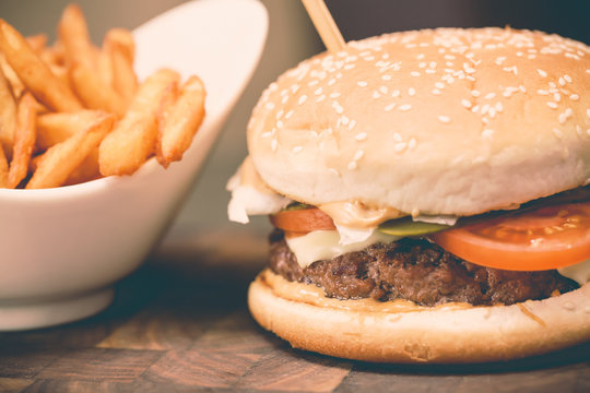 Burger with fresh tomato, cheese, meat and french fries. Selective focus and toned image