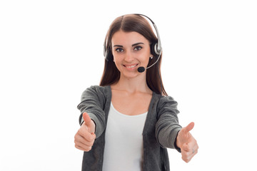 beautiful young girl in headphones and gray sweater smiles and shows the class hands