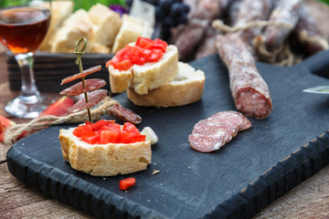Slices of salami, baguette and tomato on the wooden board