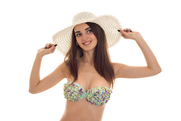 young beautiful girl with sexy body in bikini keeps hands hat on his head and smiling