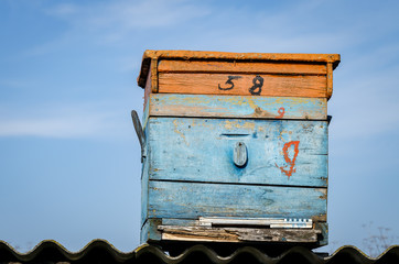 Wooden Beehive On The Roof Of A Barn On A Background Of Blue Sky.