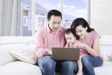 Asian family sitting on couch with laptop