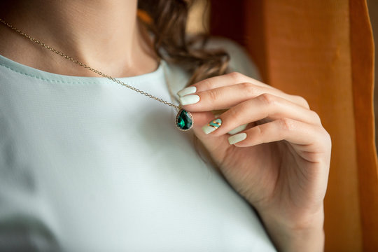 Woman holding pendant with emerald stone, luxury green jewelry