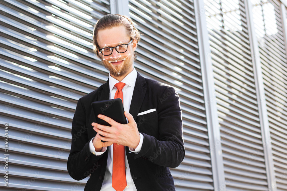 Poster a businessman with a beard and glasses smiling and looking at tablet computer. biometric verificatio