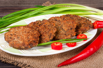 liver pancakes or cutlets with chili pepper and green onions on a wooden background