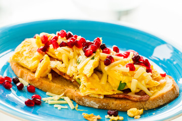 Close up of breakfast dish - omelette with green onion and ham, garnished with pomegranate