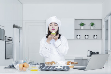 Female chef holds a cupcake in the kitchen