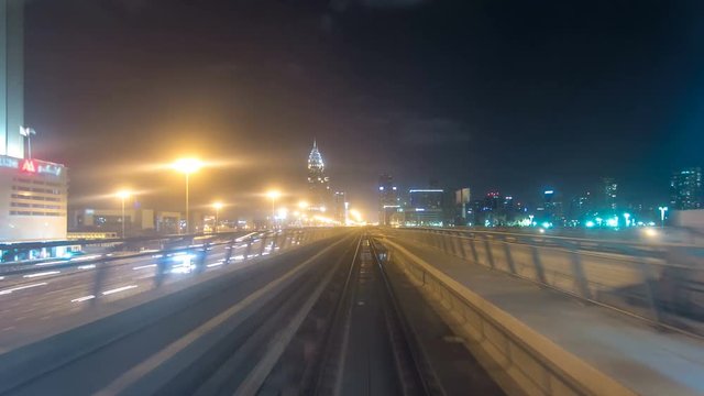 Front cabin POV view from modern driver-less metro train rush forward, along night Dubai, smooth timelapse.