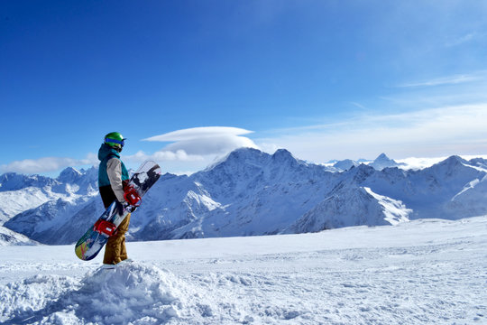 snowboarder standing with snowboard in the mountains.