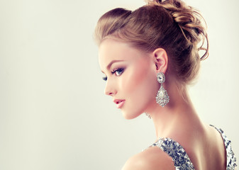 Beautiful girl with elegant hairstyle and big earrings jewelry .

