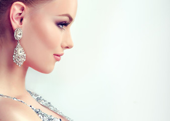 Beautiful girl with evening makeup and  large earrings jewelry .