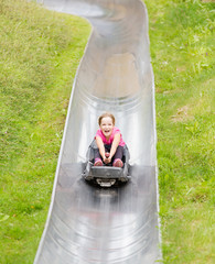 Summer bobsled track. Happy girl having fun at  amusement park