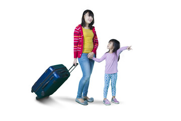 Mother and daughter carrying suitcase on studio