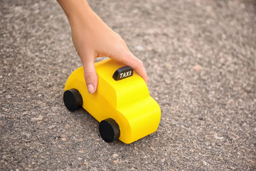 Woman holding yellow toy taxi on ground