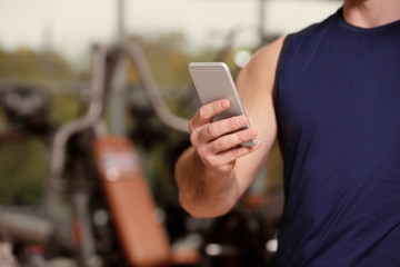 Young handsome man with cellphone in gym