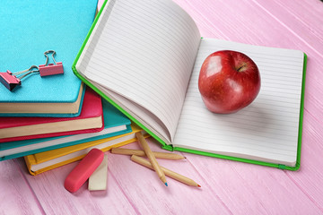 Notebooks and apple on wooden background