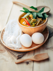 Vintage Thai traditional food style Thai vermicelli eaten with green curry chicken hot and spicy(Kanom jean keawwhan kai) on wooden background wallpaper focus one point shallow with depth of field