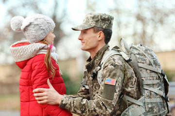Soldier in camouflage with his daughter outdoors