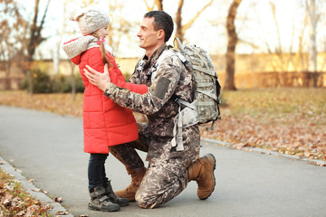 Soldier in camouflage with his daughter outdoors