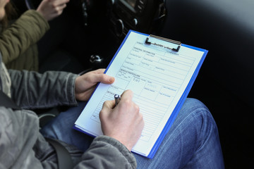 Instructor of driving school giving exam while sitting in car, closeup