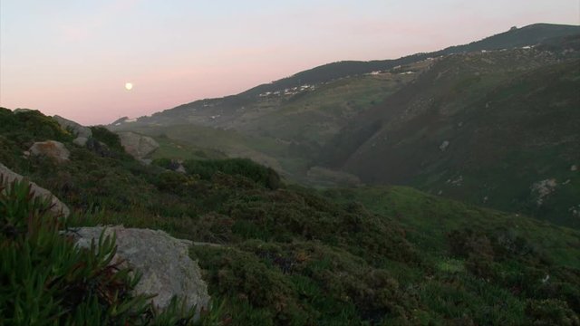 Rocky mountain with a green grass, summer evening full moon in the hills