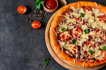 Home pizza with salami, tomato and cheese on a black background