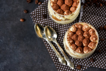 Classic tiramisu in a glass jar on a black background 