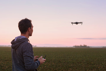 man piloting drone at sunset outdoors