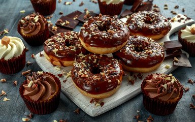 donut rings and vanilla caramel cupcakes with white and dark chocolate chippings and icing served on board