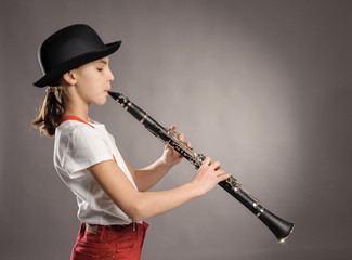 little girl playing clarinet on a gray background