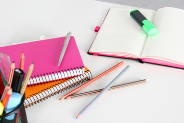 Closeup of white desktop with laptop, glasses, coffee cup, notepads and other items on blurry city background