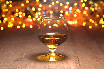 Glass of cognac, brandy or whiscy on mirror table. bottles in a bar on the background