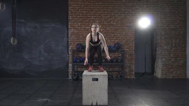 Cross-fit workout - fitness woman doing box jumps in the gym