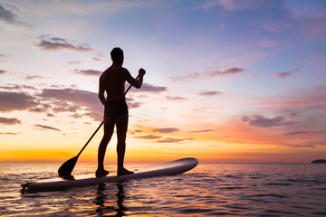 paddleboard on the beach at sunset, paddle standing in Thailand - obrazy, fototapety, plakaty