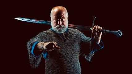 Powerful bearded knight with the sword on the dark background