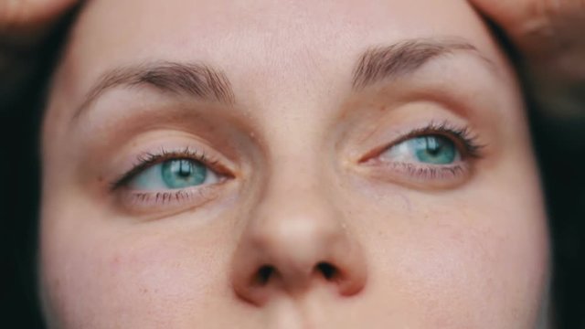Green-eyed female face looks away and up to the camera. close-up view with sad girl