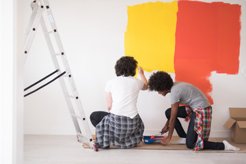 multiethnic couple painting interior wall