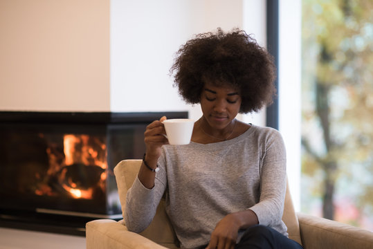 black woman drinking coffee in front of fireplace