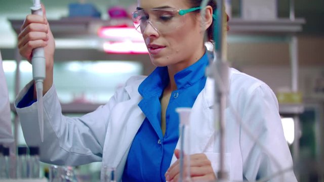 Scientist student pouring liquid in flask with pipette at chemical lab. Woman scientist doing chemical test. Chemistry student research chemical reagents in laboratory