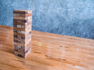 Blocks wood game or jenga game on wood table with cement wall background. Skill development game.