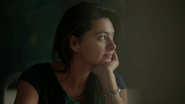 Woman in her 30s thinking about something. Girl holding her chin with her hand thinks about life and then smiles to camera spontaneously and naturally