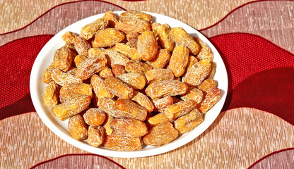 Raw date-palm isolated on the red-grey background in white plate.