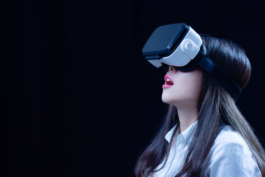 Asian Chinese young woman using vitual reality smart glasses in vitual space.low key photo